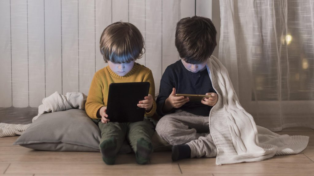 full shot kids sitting with devices